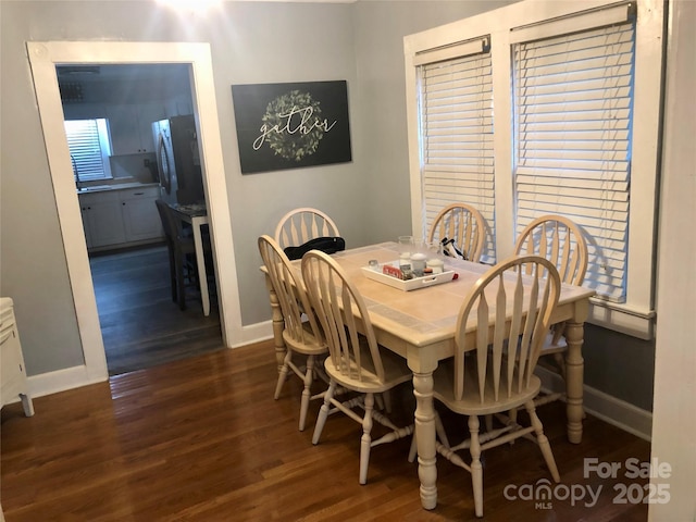 dining space with dark wood-style flooring and baseboards
