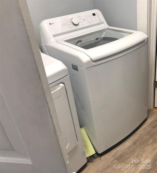 clothes washing area featuring washer and clothes dryer, laundry area, and light wood-type flooring