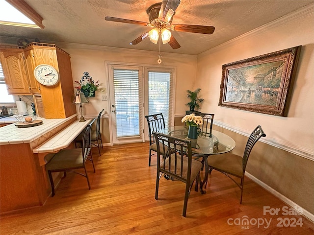 dining room featuring ceiling fan, light hardwood / wood-style floors, ornamental molding, and a textured ceiling