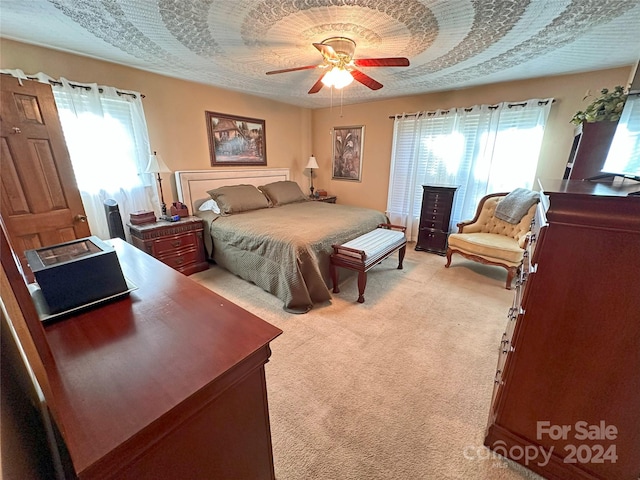 bedroom with multiple windows, ceiling fan, and light carpet