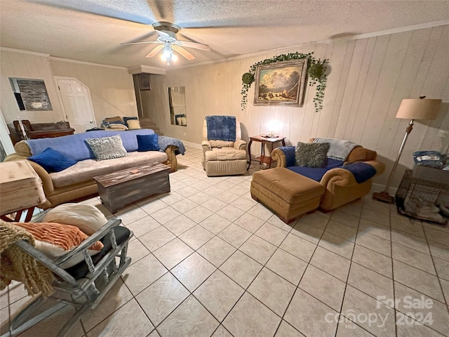 living room with ceiling fan, ornamental molding, and a textured ceiling