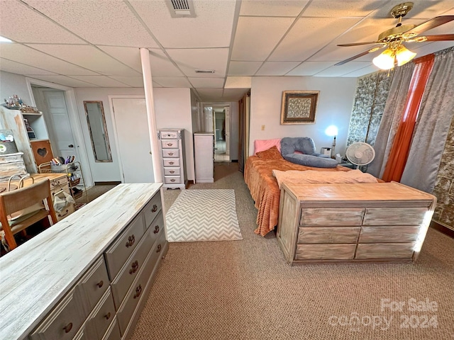 carpeted bedroom with a paneled ceiling and ceiling fan