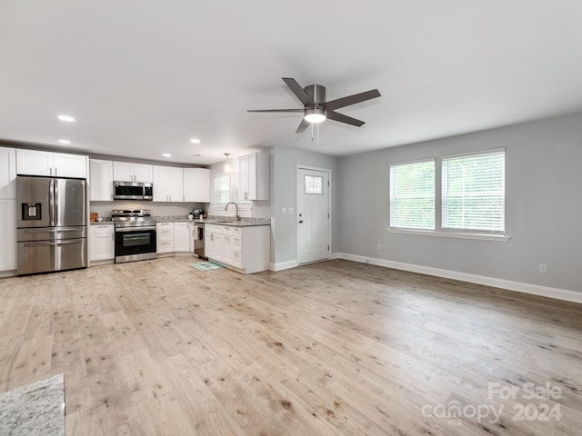 kitchen featuring white cabinetry, sink, light stone counters, appliances with stainless steel finishes, and light hardwood / wood-style flooring