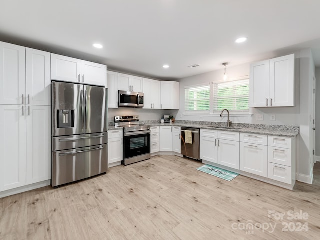 kitchen with light hardwood / wood-style floors, stainless steel appliances, white cabinets, sink, and light stone countertops