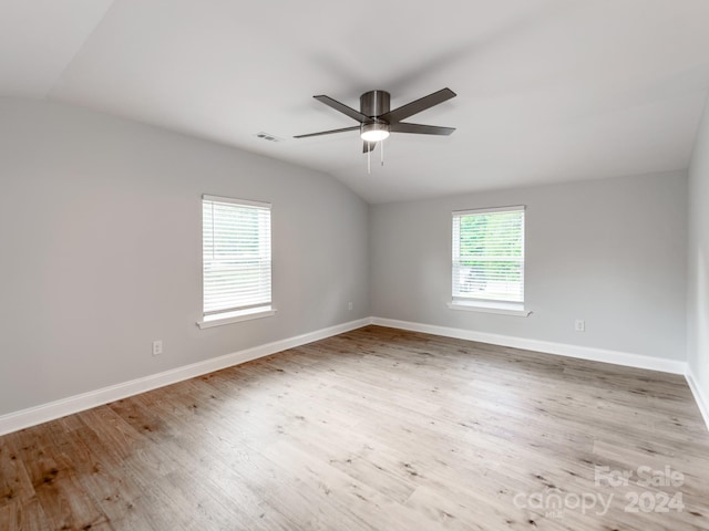 empty room with ceiling fan, a wealth of natural light, lofted ceiling, and light hardwood / wood-style floors