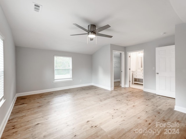 unfurnished bedroom featuring a closet, light wood-type flooring, a spacious closet, and ceiling fan