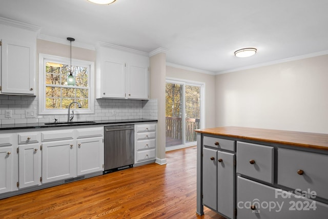 kitchen featuring light hardwood / wood-style floors, white cabinets, sink, stainless steel dishwasher, and decorative light fixtures