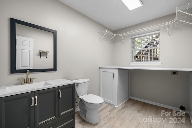 bathroom featuring hardwood / wood-style floors, vanity, toilet, and a textured ceiling