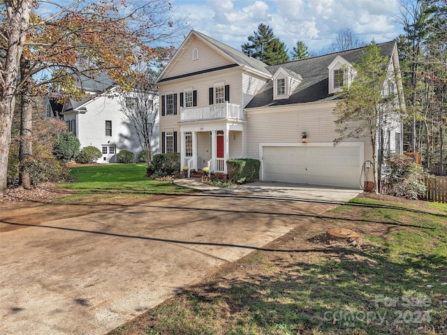 view of front of home featuring a front lawn, a balcony, and a garage