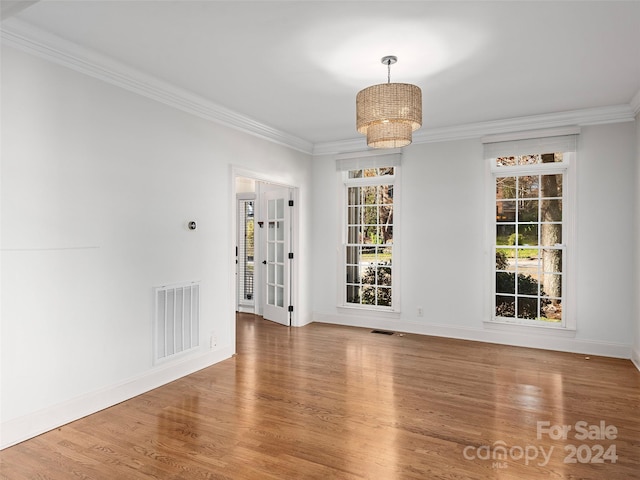 spare room featuring a notable chandelier, hardwood / wood-style flooring, and crown molding