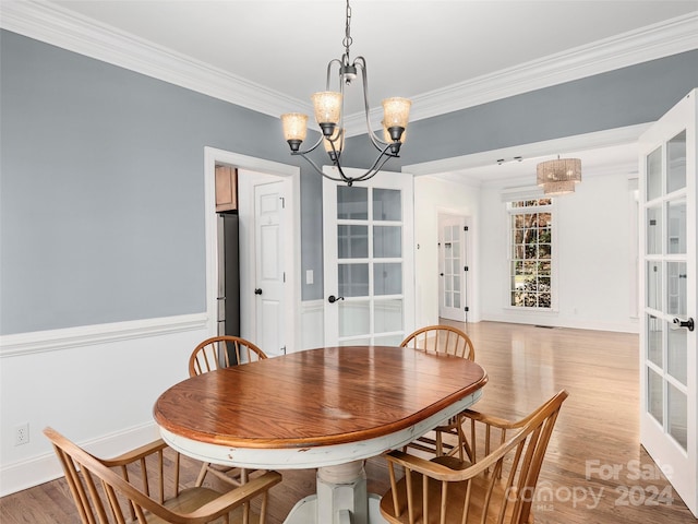 dining room featuring an inviting chandelier, light wood-type flooring, french doors, and ornamental molding