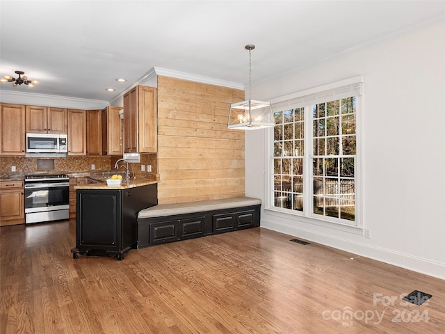 kitchen featuring light stone counters, backsplash, appliances with stainless steel finishes, a notable chandelier, and dark hardwood / wood-style floors