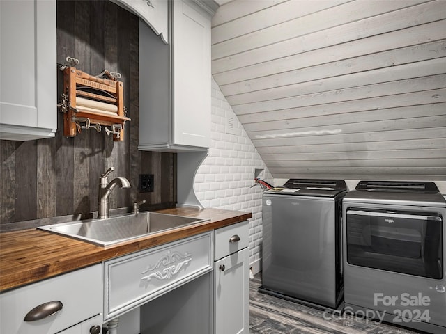 laundry area featuring wood walls, cabinets, sink, hardwood / wood-style floors, and independent washer and dryer