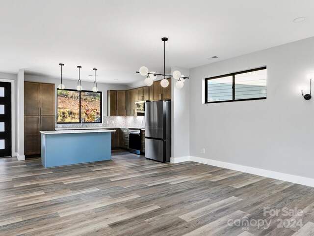 kitchen featuring a healthy amount of sunlight, pendant lighting, appliances with stainless steel finishes, and a center island