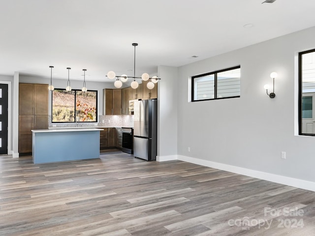 kitchen with hanging light fixtures, a wealth of natural light, stainless steel fridge, and a center island