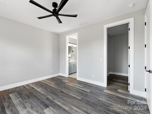 unfurnished bedroom featuring dark hardwood / wood-style floors, ceiling fan, connected bathroom, and a walk in closet