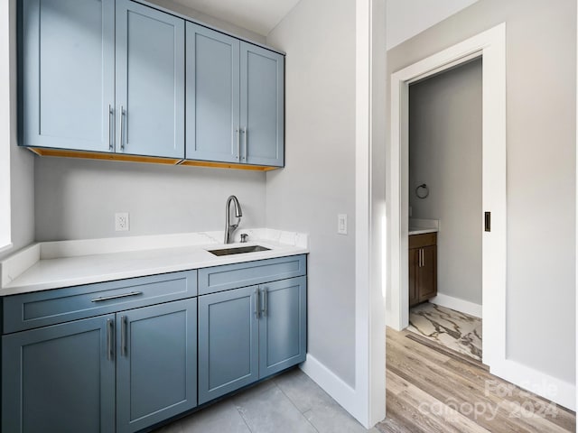 interior space with blue cabinetry, sink, and light hardwood / wood-style flooring