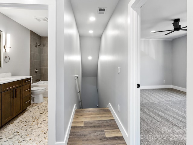 full bathroom with vanity, tiled shower / bath combo, hardwood / wood-style flooring, toilet, and ceiling fan