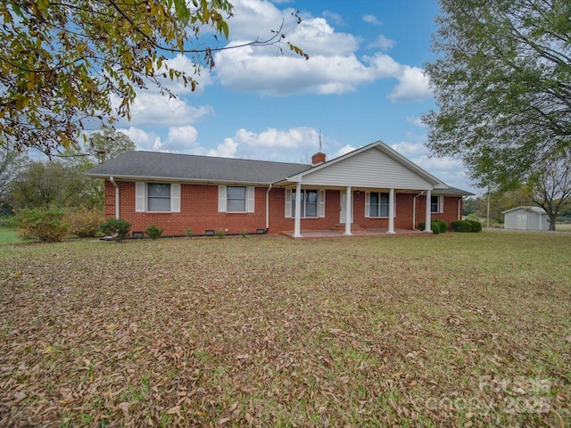 single story home featuring covered porch, a shed, and a front lawn