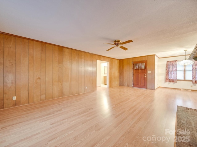 unfurnished room featuring ceiling fan, wood walls, light hardwood / wood-style floors, and ornamental molding