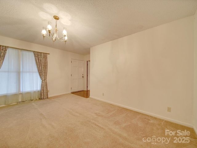 unfurnished room featuring carpet floors, a textured ceiling, and a chandelier