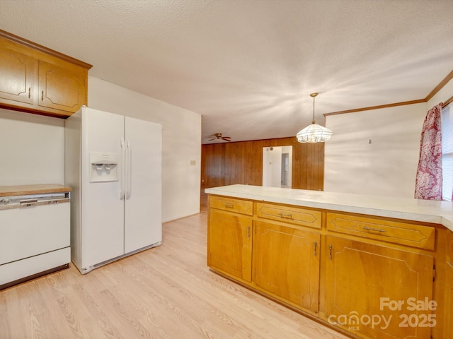 kitchen with a textured ceiling, wooden walls, white refrigerator with ice dispenser, light hardwood / wood-style flooring, and hanging light fixtures