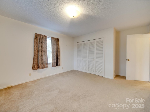 unfurnished bedroom with a closet, light colored carpet, and a textured ceiling