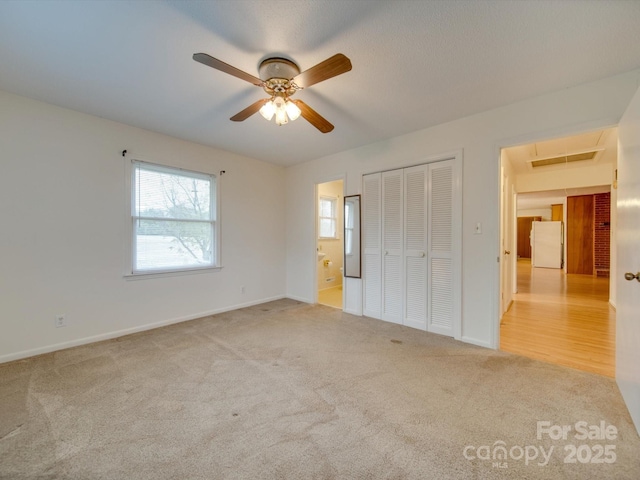 unfurnished bedroom featuring ceiling fan, a closet, white fridge, and light carpet