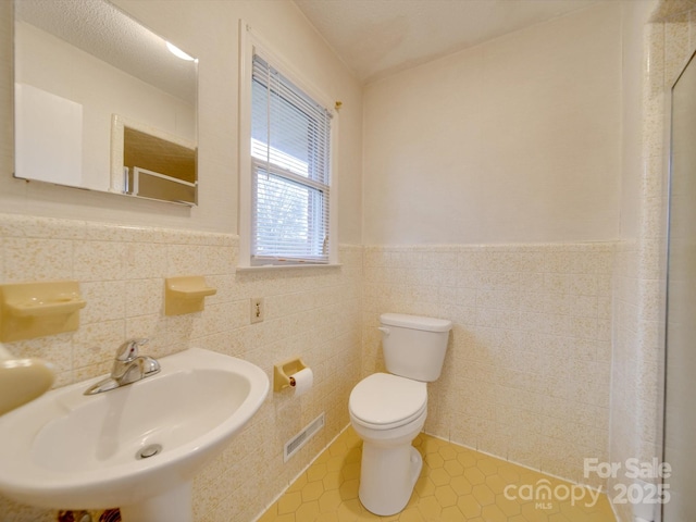 bathroom with tile patterned floors, sink, tile walls, and toilet