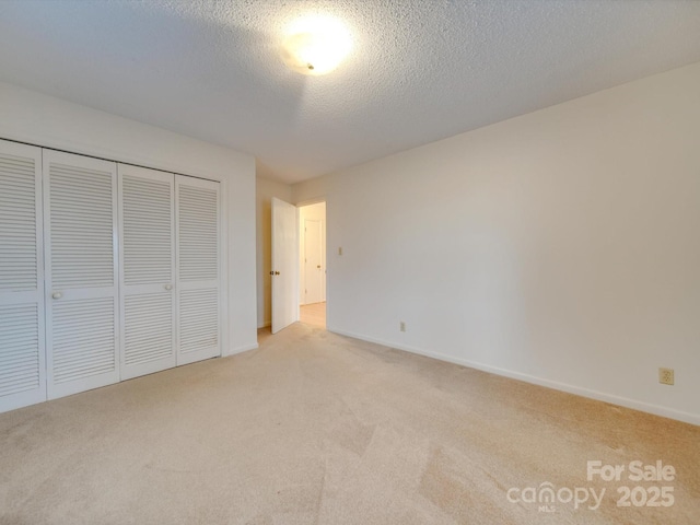 unfurnished bedroom with a textured ceiling, light colored carpet, and a closet