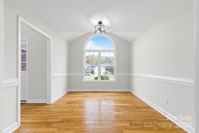 unfurnished room featuring light hardwood / wood-style floors and vaulted ceiling