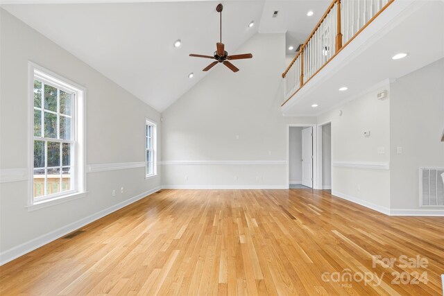 unfurnished living room featuring high vaulted ceiling, a healthy amount of sunlight, light wood-type flooring, and ceiling fan