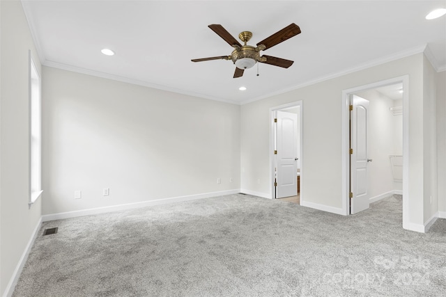 unfurnished bedroom with ceiling fan, light carpet, a walk in closet, and ornamental molding