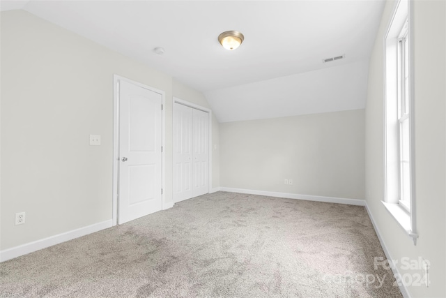 unfurnished bedroom with carpet flooring and lofted ceiling