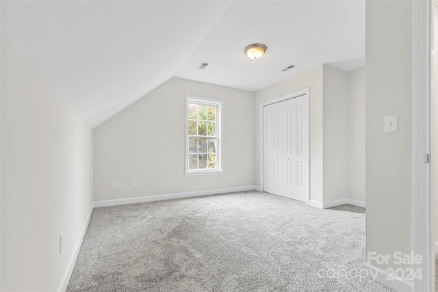 bonus room with vaulted ceiling and light colored carpet