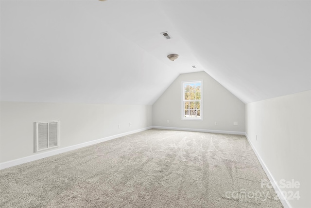 additional living space featuring light colored carpet and lofted ceiling