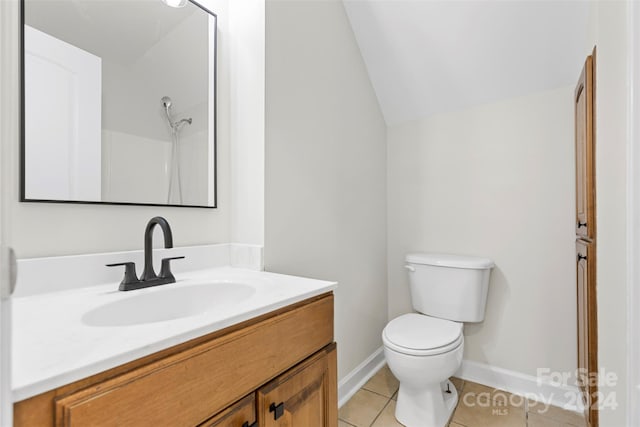 bathroom featuring toilet, vanity, vaulted ceiling, and tile patterned flooring