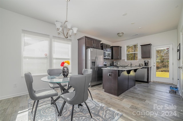 kitchen with a center island, hanging light fixtures, stainless steel appliances, light hardwood / wood-style flooring, and decorative backsplash