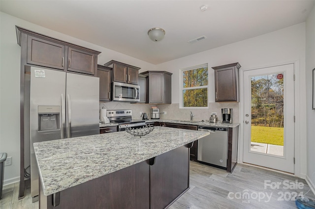 kitchen featuring sink, a center island, stainless steel appliances, light hardwood / wood-style floors, and decorative backsplash