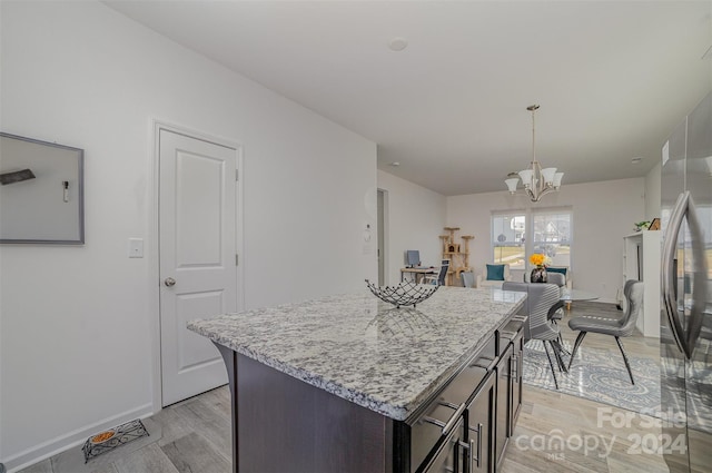 kitchen featuring light hardwood / wood-style flooring, a kitchen island, hanging light fixtures, a notable chandelier, and dark brown cabinets