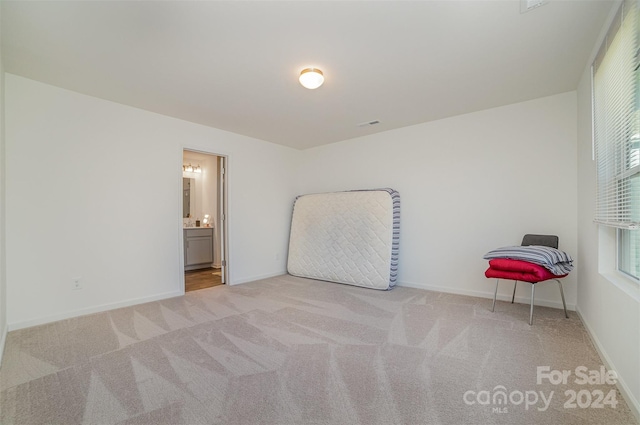 unfurnished bedroom with connected bathroom and light carpet