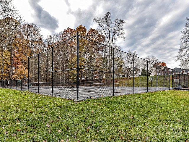 view of tennis court with a yard