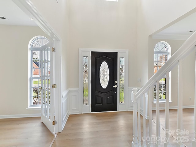 foyer entrance with light wood-type flooring, a wealth of natural light, and crown molding