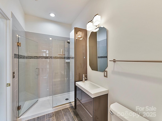 bathroom with a shower with door, vanity, and toilet