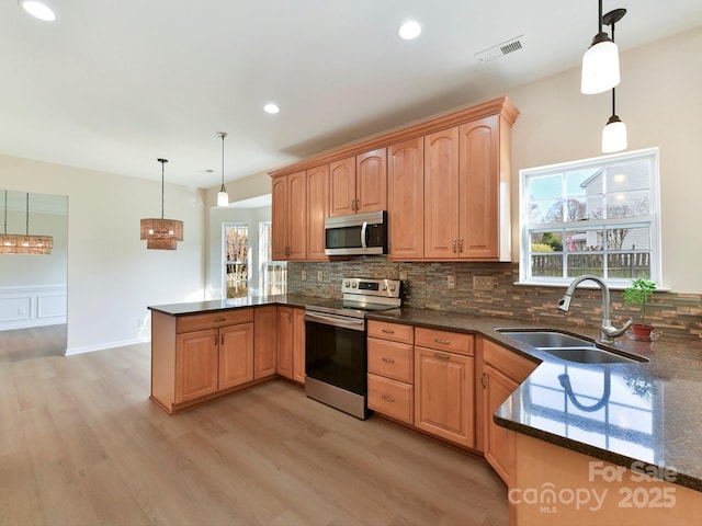 kitchen featuring kitchen peninsula, sink, pendant lighting, and appliances with stainless steel finishes