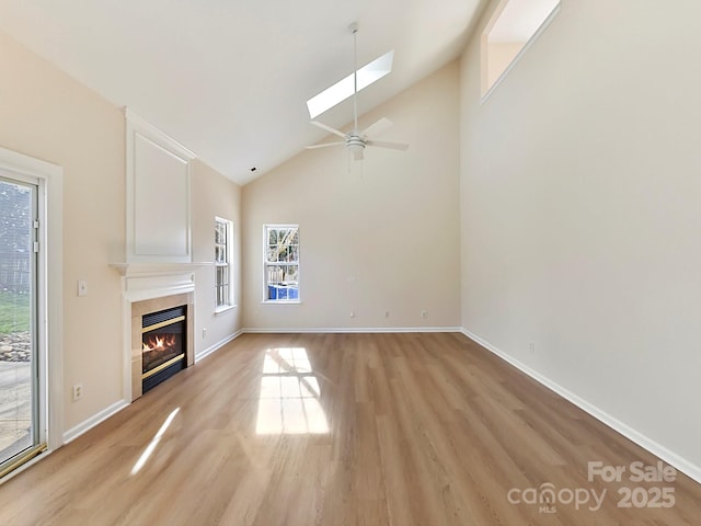 unfurnished living room featuring ceiling fan, light hardwood / wood-style flooring, and lofted ceiling with skylight