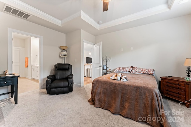 carpeted bedroom featuring a raised ceiling, ceiling fan, crown molding, and ensuite bathroom