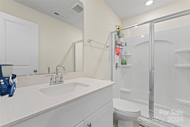 bathroom with vanity, a shower with shower door, and toilet