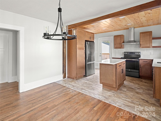 kitchen with hanging light fixtures, a center island, stainless steel fridge, black / electric stove, and wall chimney range hood