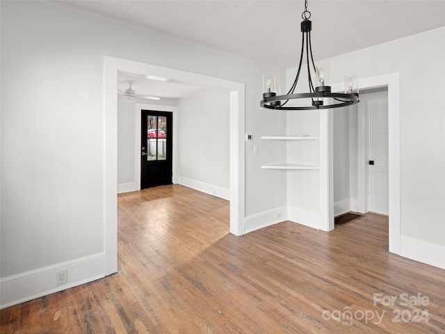 unfurnished dining area with wood-type flooring and ceiling fan with notable chandelier